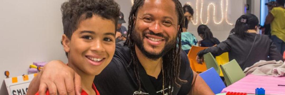 a father and son smiling and building lego. 