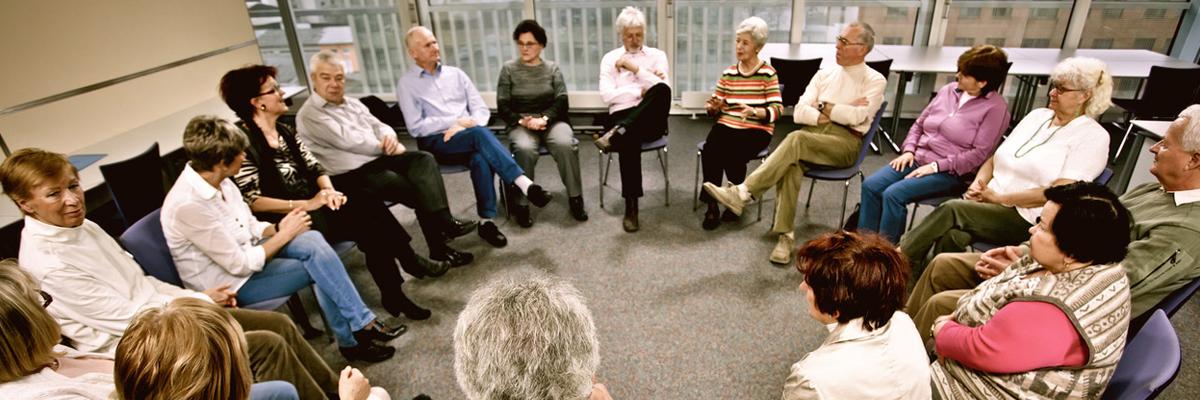 Un grand groupe de 17 personnes se réunit dans un groupe de soutien. Ils sont assis en cercle.