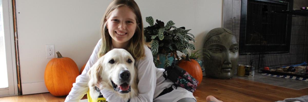 Dani and George sitting on her living room floor; Dani has her arm around George and both are smiling for the camera