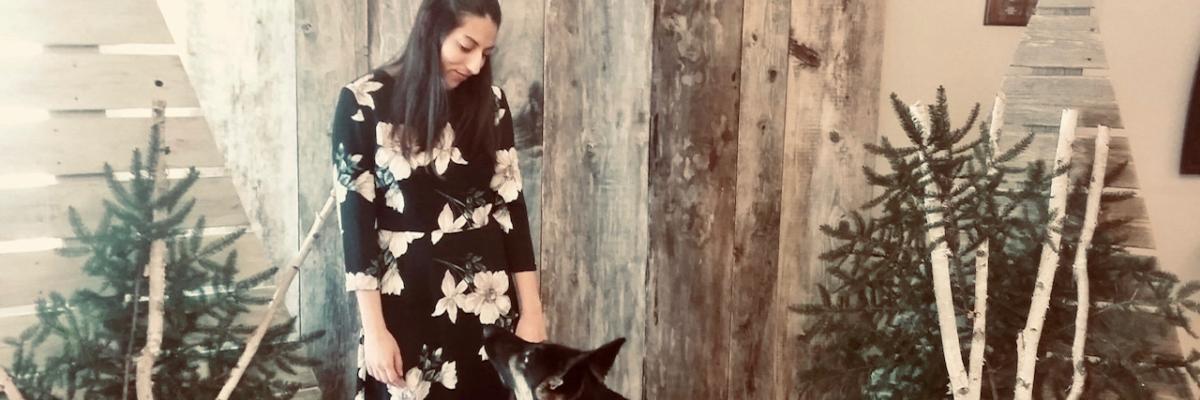 Stela Trudeau and her German Shepherd guide dog exchanging a look at one another, in front of a Christmas-themed photo backdrop.