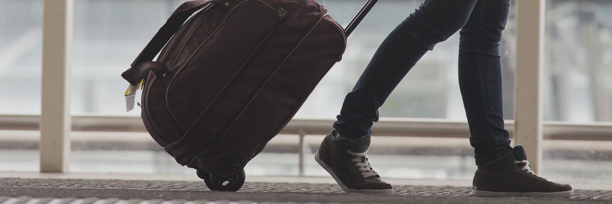 A young woman pulls their luggage in the airport terminal.