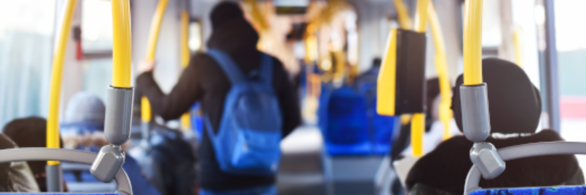 Interior of a city bus. Commuters sit and stand inside the bus.