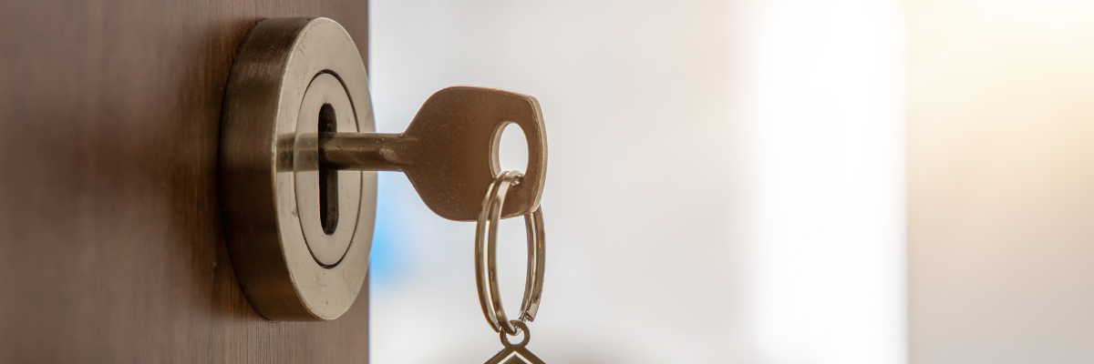 Une porte ouverte qui mène à un nouvel appartement. Un trousseau de clés pend dans la serrure de la porte.