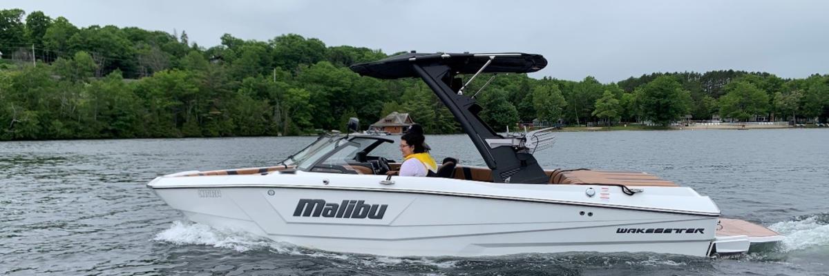 Bateau de ski nautique blanc sur le lac avec les mots « Malibu » et « Wakesetter » sur le côté.