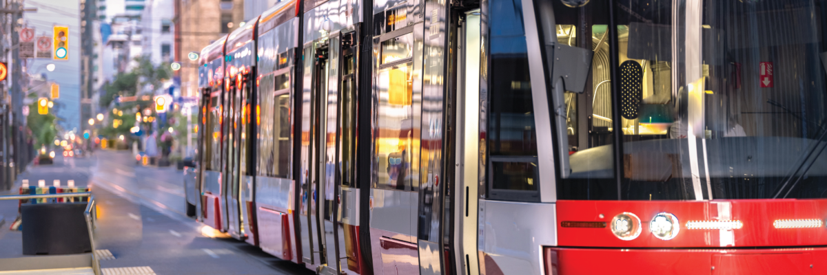 A streetcar glides along a busy city street and approaches a stop.