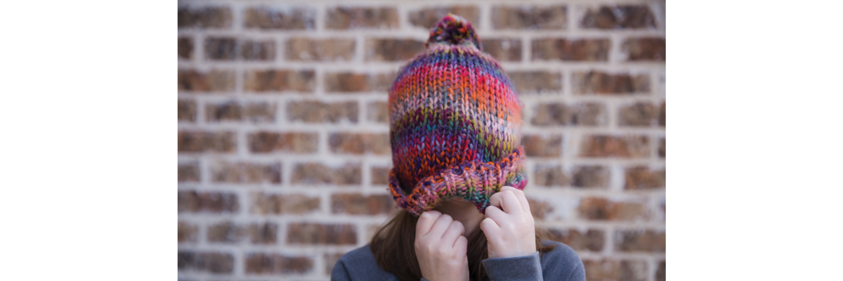 Une jeune fille descend son bonnet d'hiver coloré sur son visage.