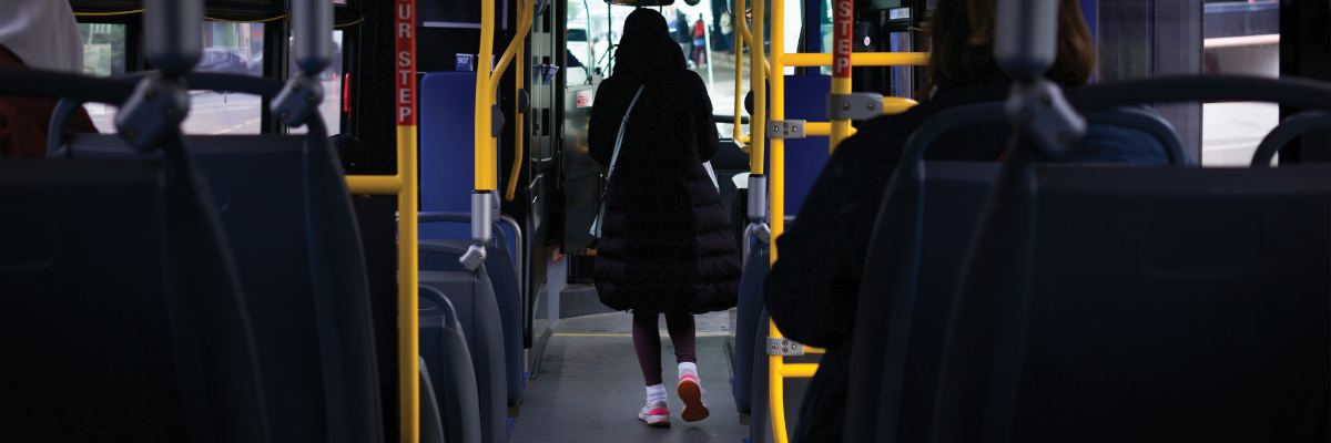 L’intérieur d’un autobus urbain. L’image est prise de l’arrière de l’autobus, où une personne avance dans l’allée vers la porte avant.