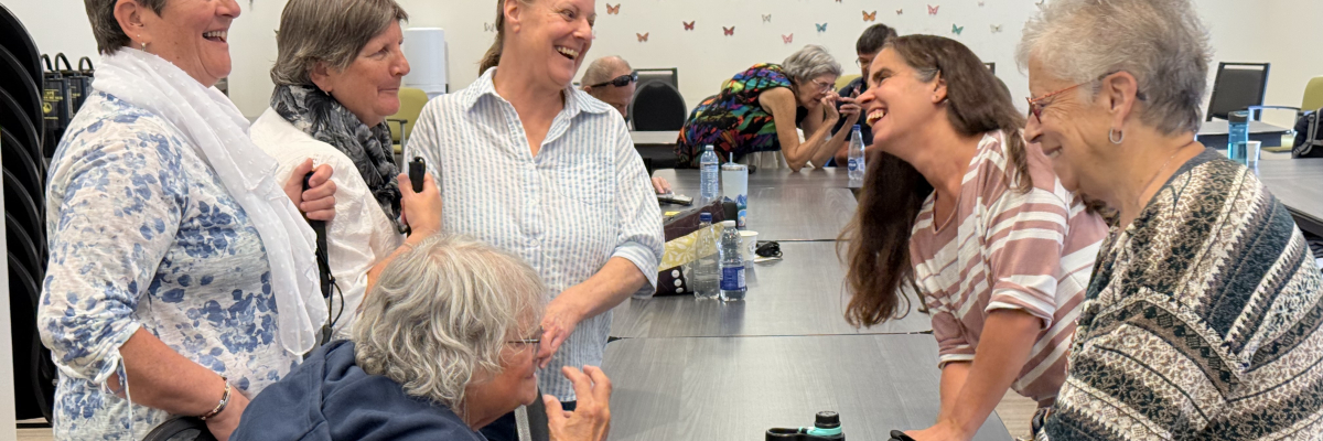 Lyne Dubé, chef de programme en technologie adaptée chez INCA, discute et rit avec cinq participantes.