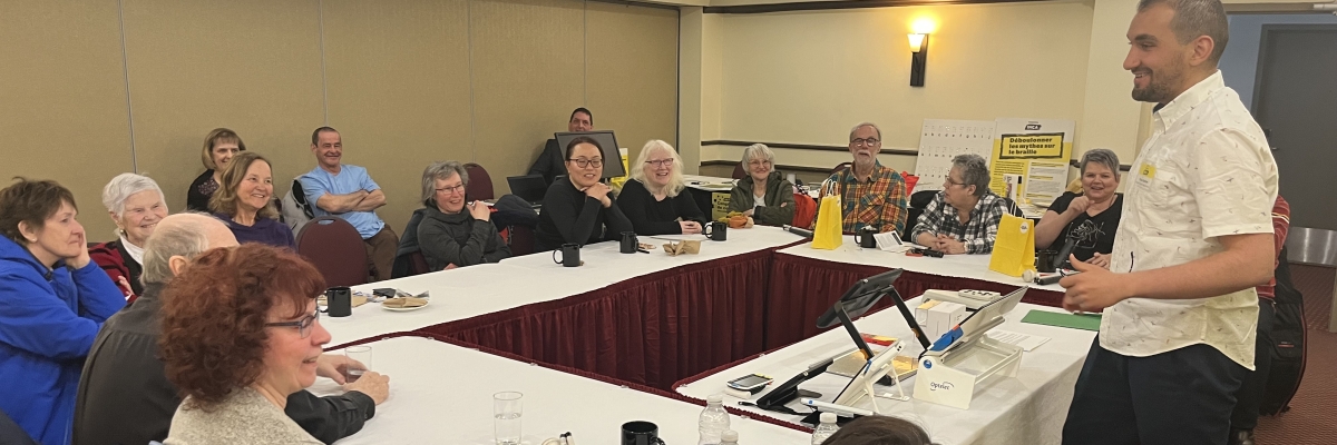 Mazen sourit en présentant des produits devant une quinzaine de personnes assise derrière des tables.