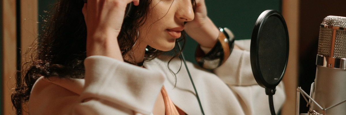 Une jeune femme porte un casque et enregistre un audio dans un studio