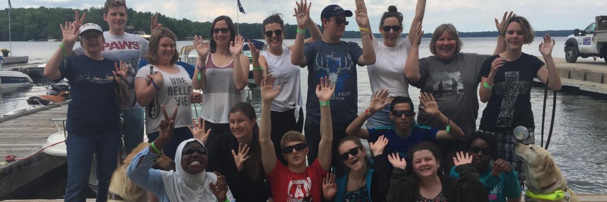 Des participants posant en groupe sur un quai et saluant la caméra.