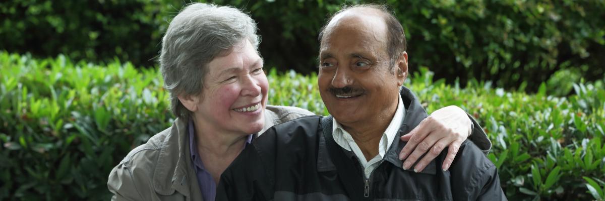 Woman and man sitting on a bench smiling. 