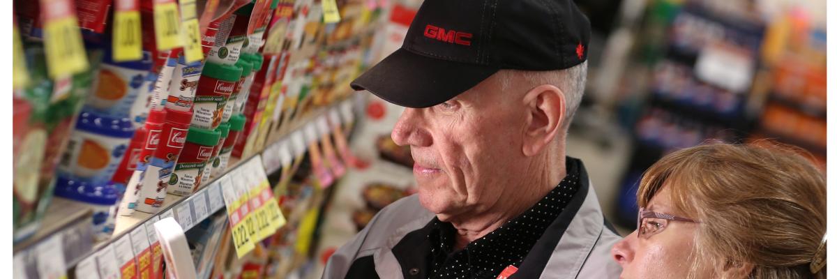 An older man and younger woman looking at price tags in a grocery store