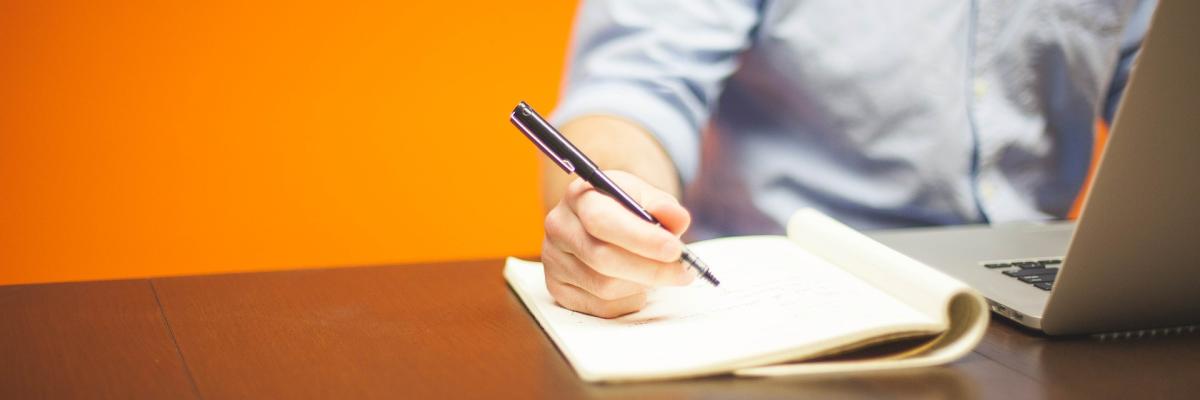 A man uses a notebook and laptop.