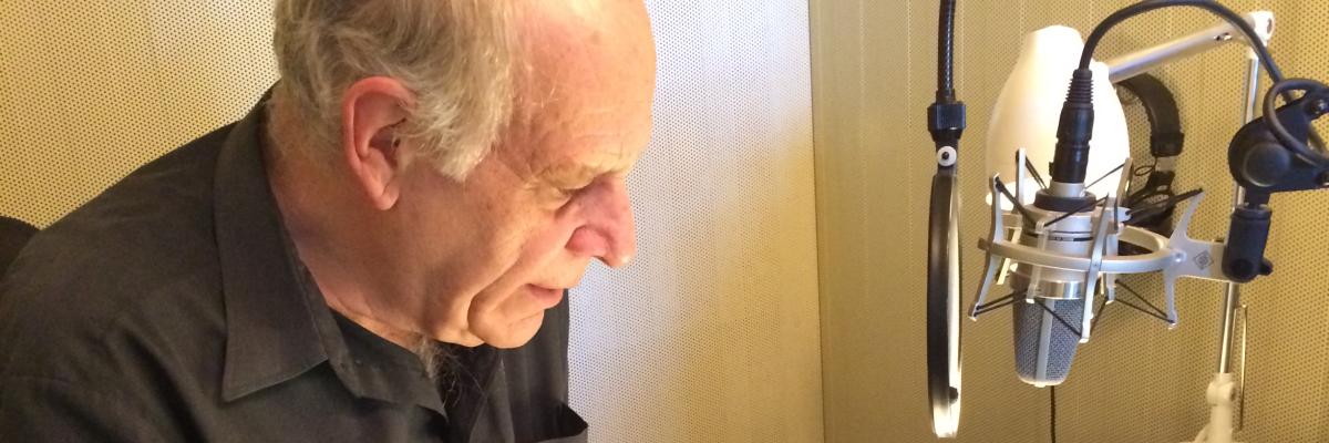 Pierre Germain lit un livre devant un micro