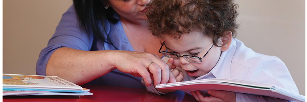 une mère et son enfant lisent un livre tactile en braille.