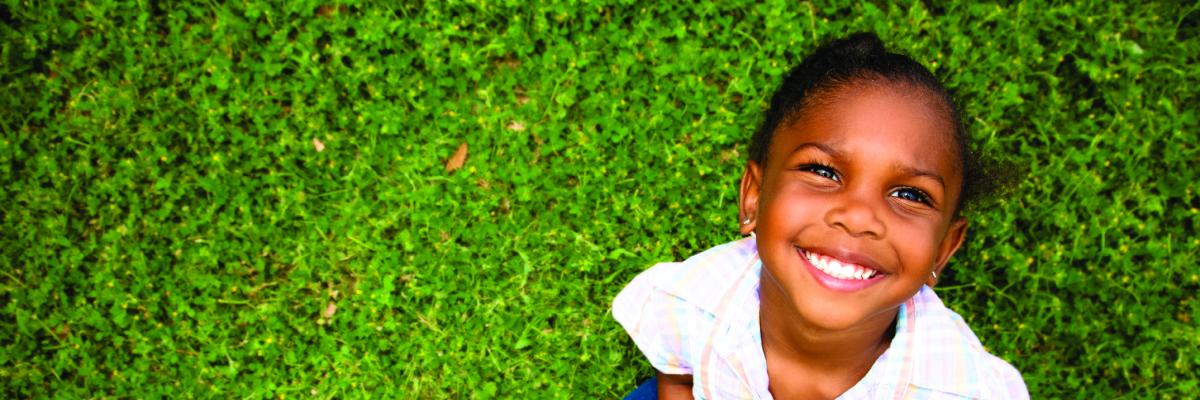 Jeune fille souriante, assise sur la pelouse