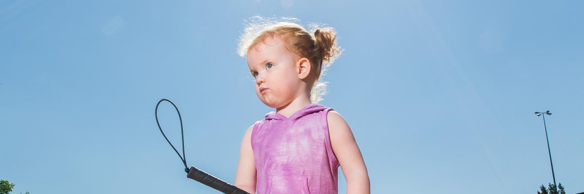 young girl outside with white cane