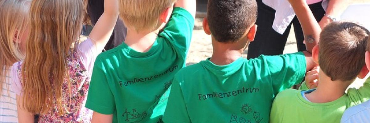 Un groupe de jeunes enfants lève les mains en l'air pour répondre à une question.