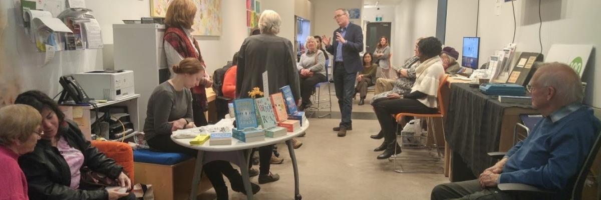 Photo of a Book Launch event with Terry Fallis speaking with group of CNIB participants.