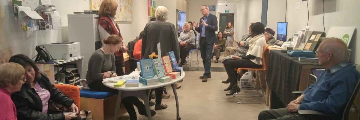 Photo of a Book Launch event with Terry Fallis speaking with group of CNIB participants.