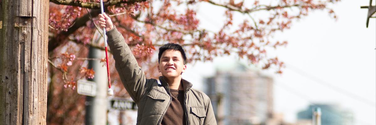 Male teenager triumphantly raising his white cane into the air.