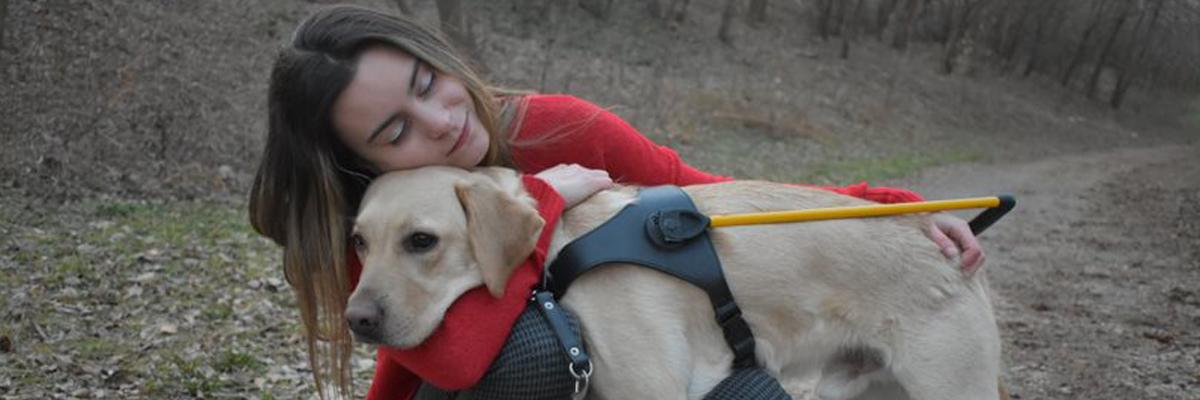 Danika hugging a Lab/Golden Retriever cross in a yellow harness.