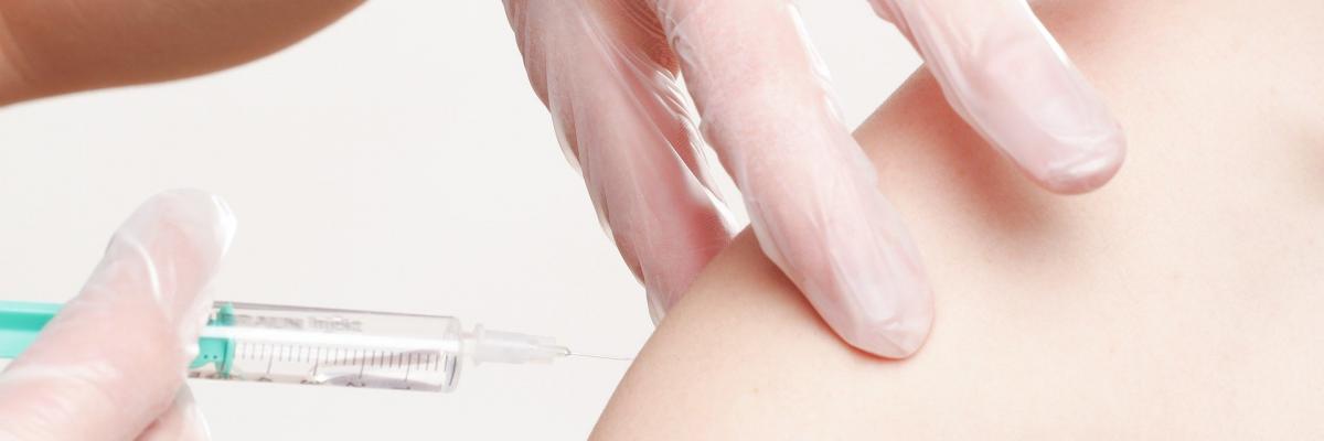 Une personne recevant un vaccin. Un bras sans manche est injecté avec une aiguille.