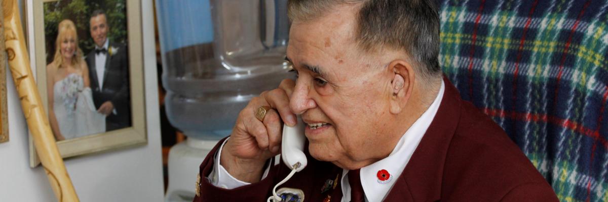 Un homme âgé sourit en parlant au téléphone.  