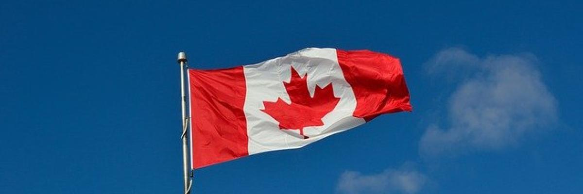 A Canadian flag waves in a clear, blue sky.