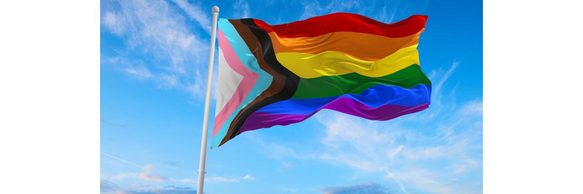Un drapeau inclusif LGBTQ flotte dans un ciel nuageux.