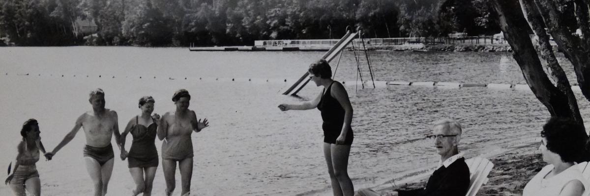 An old black and white photograph of people at CNIB Lake Joe running into the lake.