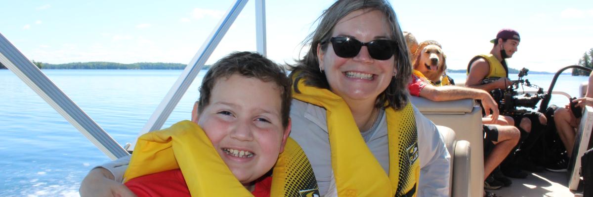 "Un garçon souriant et une femme en gilet de sauvetage assis sur le pont du bateau"