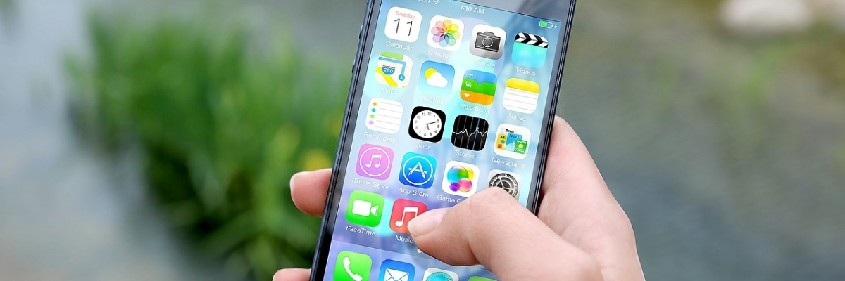 Une main tient un téléphone intelligent. On voit les icônes de plusieurs applications.  