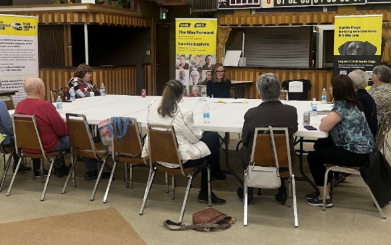 Neuf membres de la communauté sont assis autour d’une table et discutent.