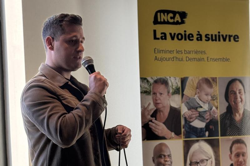 Johann parle au micro. Derrière lui, se trouve une bannière jaune d'INCA avec le texte "La Voie à suivre".