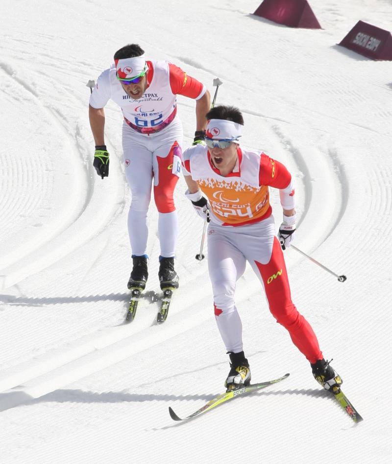 Brian McKeever et un autre skieur en tenue de compétition descendent la piste.