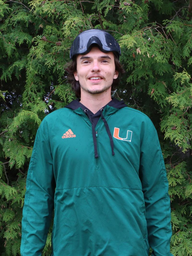 Chayse Zehr se tient devant un arbre vert. Il est vêtu d'une tenue de sport et porte un masque.