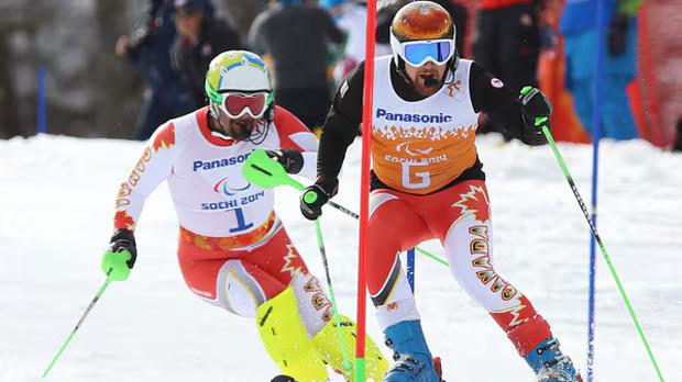 Chris Williamson en compétition à Sotchi en 2014, photographié avec son guide. Source : CBC.