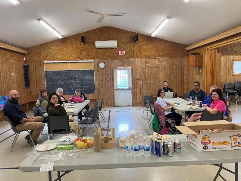 Les participants se sont réunis lors d'un atelier d'information sur le programme de soutien juridique. Une dizaine de participants sont assis autour de deux tables dans une salle de réunion communautaire, accompagnés d'une table avec des rafraîchissements.