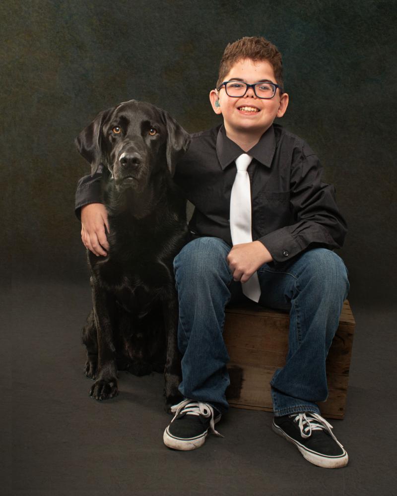 Kaiden et son compagnon canin Flinn, un labrador retriever noir, posent ensemble pour une photo.