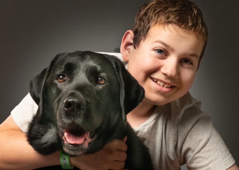 Ollie sourit et enlace Hope, son chien compagnon d'INCA.