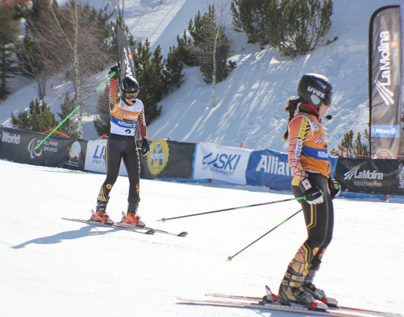 Viviane Forest et un autre skieur en tenue de compétition font une pause au pied d'une piste enneigée.
