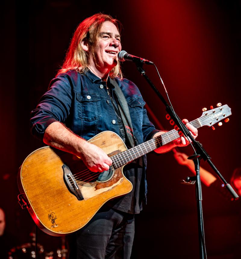 Le musicien Alan Doyle se tient sur scène devant un micro, une guitare à la main