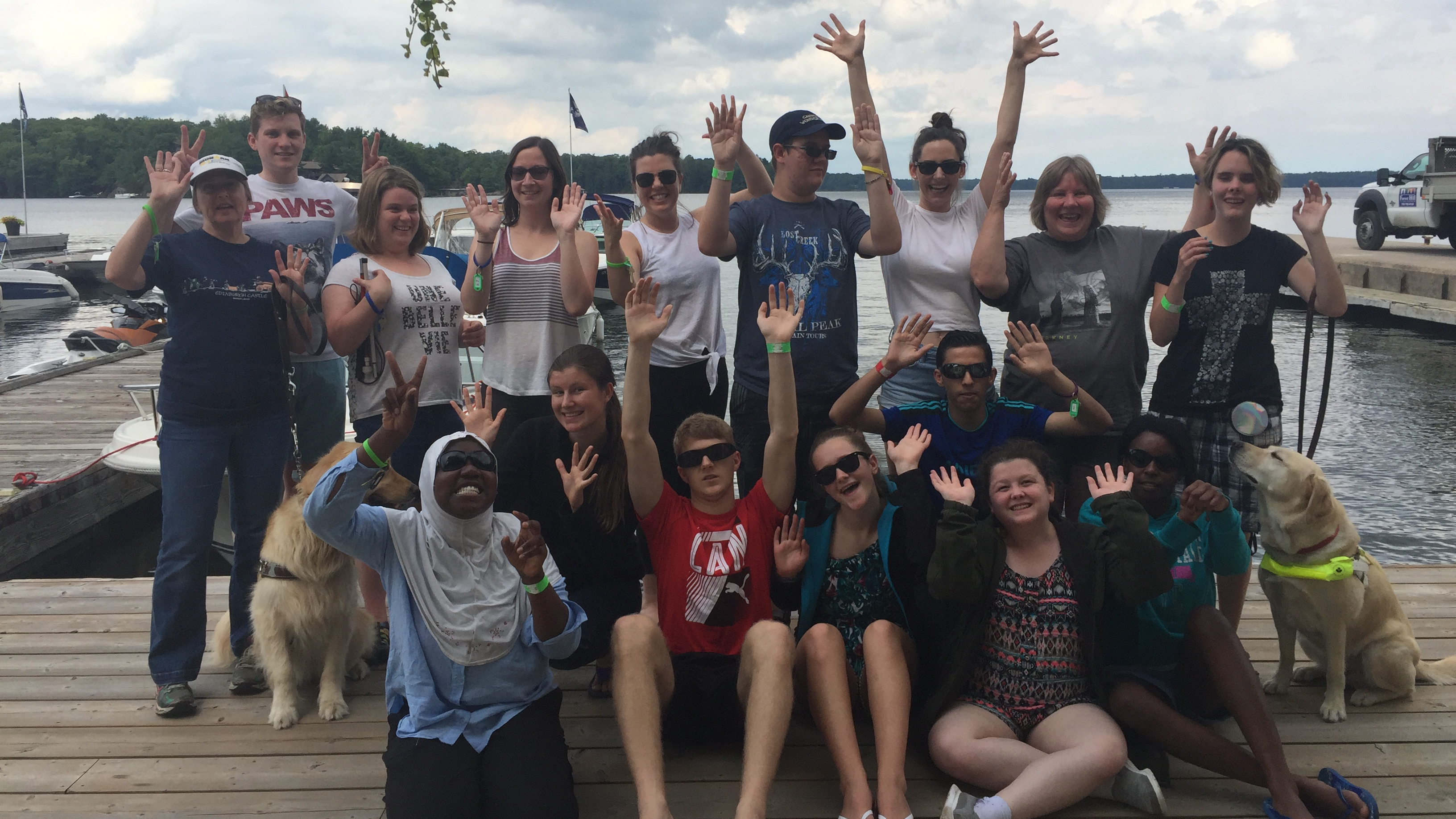 Participants posant en groupe sur un quai et saluant la caméra (prise en 2018).
