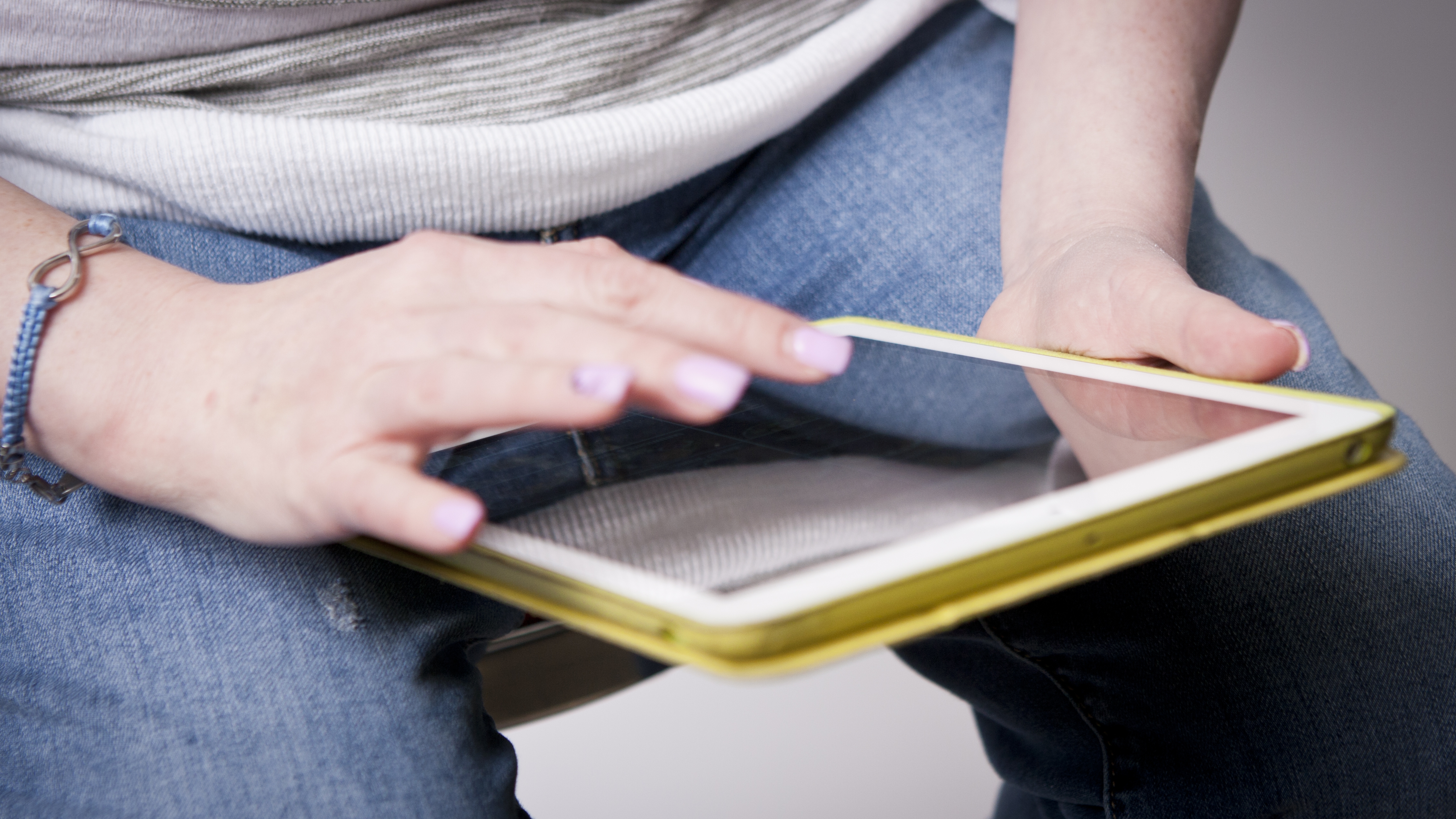 Une femme tient une tablette iPad sur ses genoux