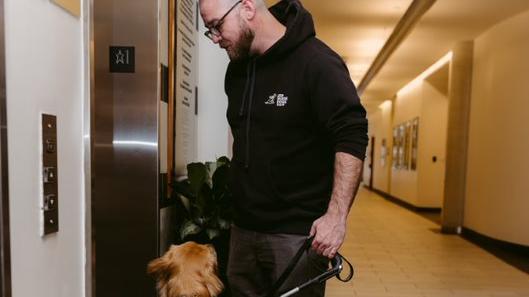Rob et un chien-guide en formation trouvent une porte d'ascenseur