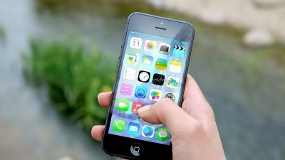 Une main tient un téléphone intelligent. On voit les icônes de plusieurs applications.  