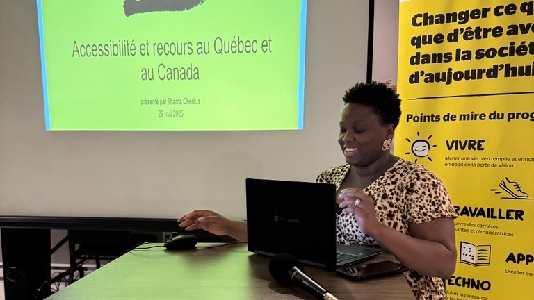 Thama assise derrière une ordinateur et un micro présente un Powerpoint.