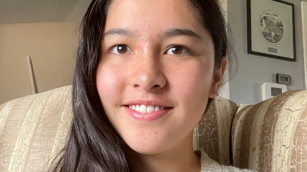 Portrait d'Anna Kim souriante, assise sur un canapé.